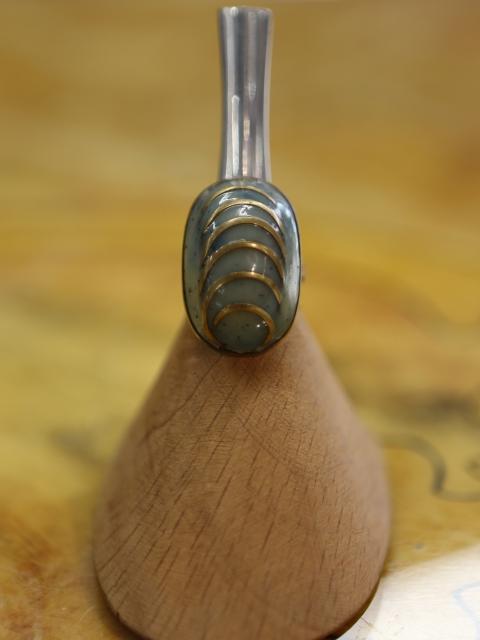 <p>anello con montatura in metallo regolabile e pietra sintetica e inserti dorati</p>